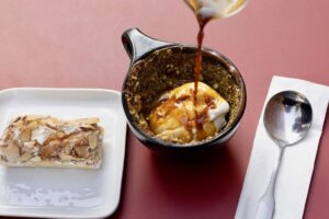 Coffee being poured with a pastry on the side